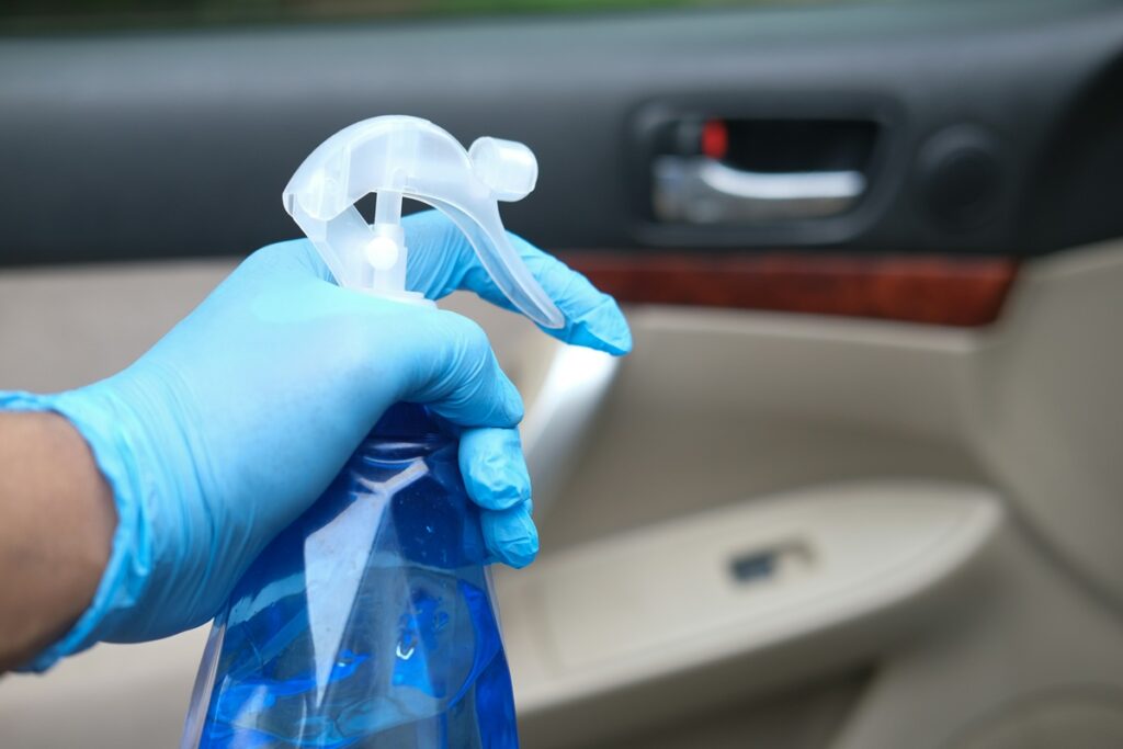 A hand with a blue plastic glove holds a clear plastic water bottle.