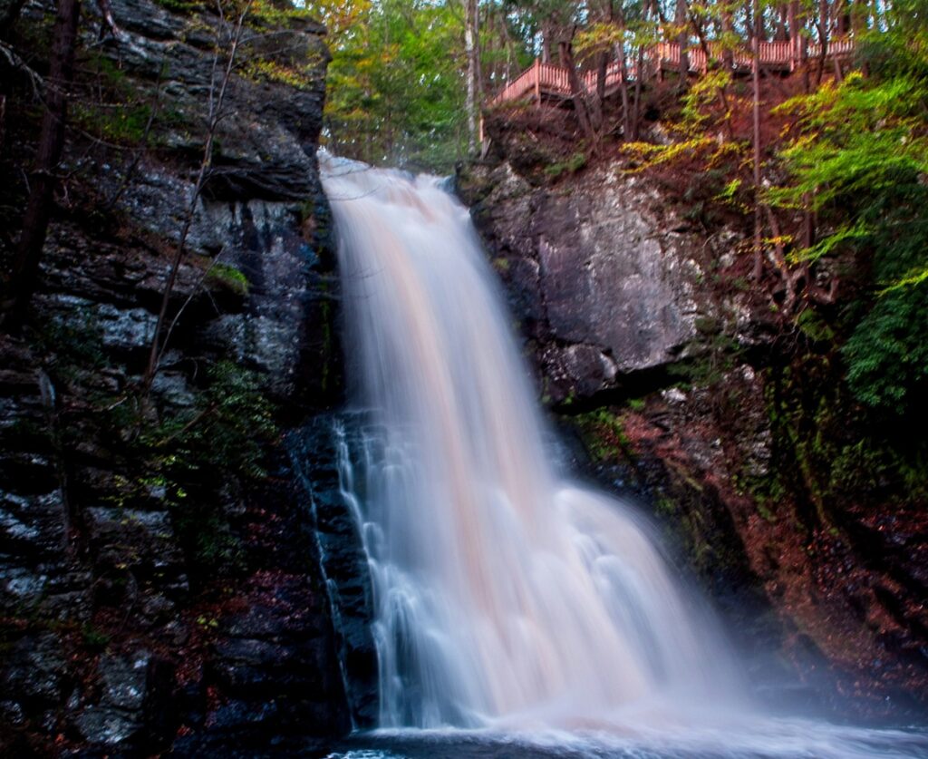 A waterfall, between two massive chiseled rocks, drops into a natural pool.