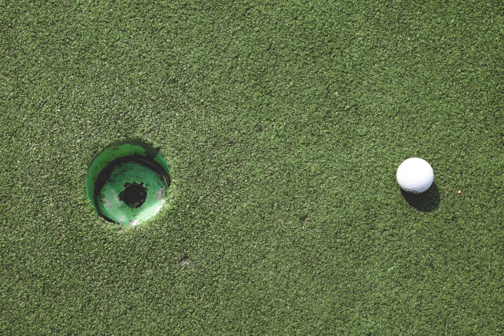 A golf ball sits inches from a hole at a mini golf course.